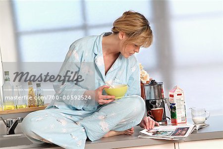 Woman Having Cereal and Reading Magazine