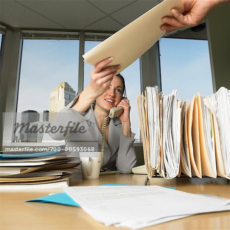 Woman Receiving File From Office Staff While Talking On the Phone