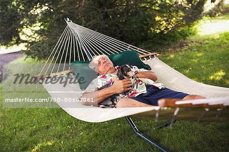 Mature Man Napping in Hammock With Dog