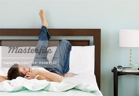 Boy Lying on Bed with Cellular Phone