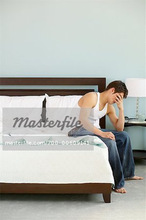 Man on Bed with Head in Hands