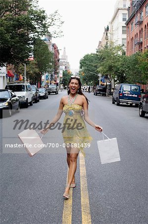 Woman Walking in Middle of Road Holding Shopping Bags