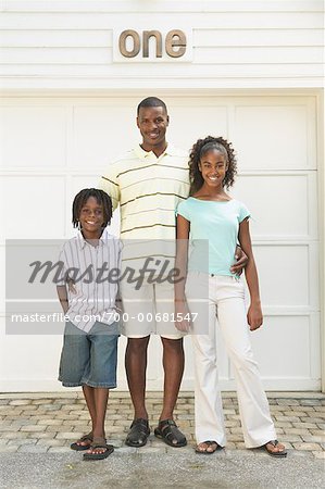 Father and Children Standing In Front of Garage