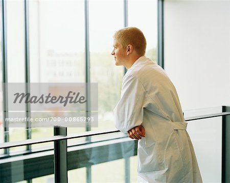 Man in Lab Coat Looking Out Window