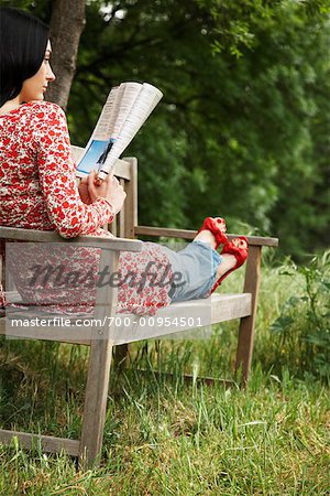 Woman Sitting On Park Bench Reading