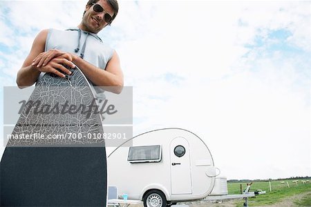 Man Holding Skimboard in Front of Trailer