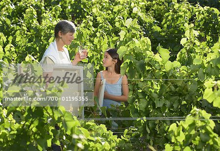 Grandmother and Granddaughter Standing in Vineyard, Holding Painting Supplies