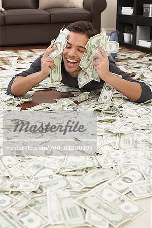 700-01200198em-Man-Lying-on-Pile-of-Money.jpg