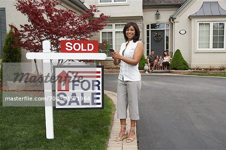 Real Estate Agent by House with Sold Sign