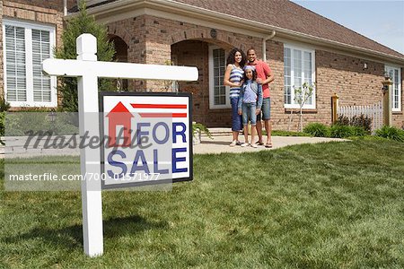 Portrait of Family by House with For Sale Sign