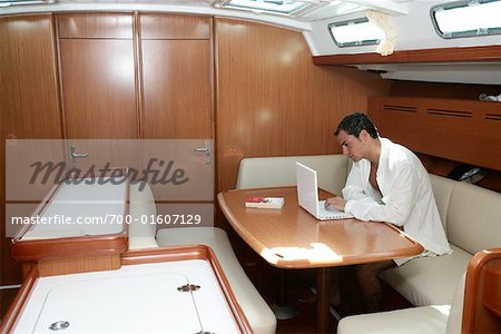 Man in Boat Cabin with Laptop Computer, Dodecanese, Greece