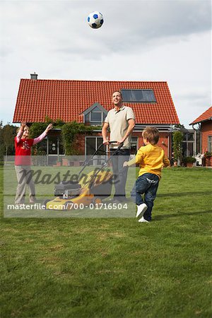 Dad Mowing the Lawn While Kids Play Soccer