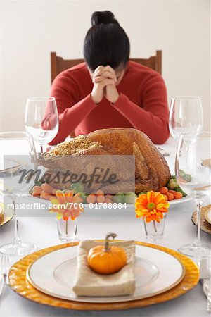 Woman Saying Grace at Thanksgiving Dinner