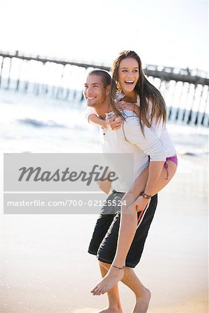 Man giving and adult woman a piggyback ride laughing and having fun in San  Diego, California. Stock Photo