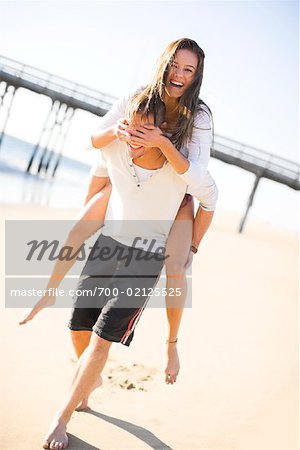 Man giving and adult woman a piggyback ride laughing and having fun in San  Diego, California. Stock Photo