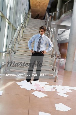 Businessman Looking at Papers Scattered on the Floor