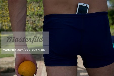 Rear View of Man With Cell Phone Tucked in His Shorts, Holding an Orange, Mallorca, Baleares, Spain