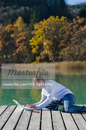 Man Sitting on Dock, Using Laptop, Fuschlee, Fuschl am See, Salzkammergut, Salzburger Land, Austria