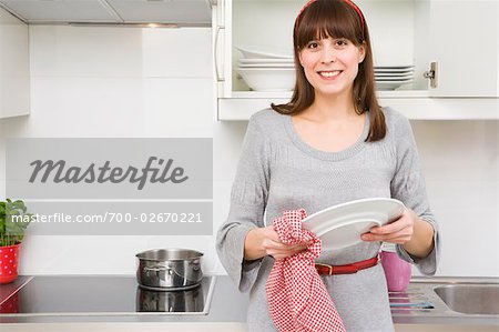 Portrait of a smiling young woman washing dishes Stock Photo by vadymvdrobot