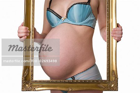 Pregnant woman in bra and panties holding stomach Stock Photo