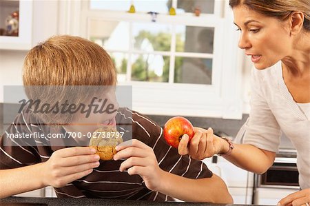 Mother Trying to Get Son to Eat an Apple Instead of a Cookie