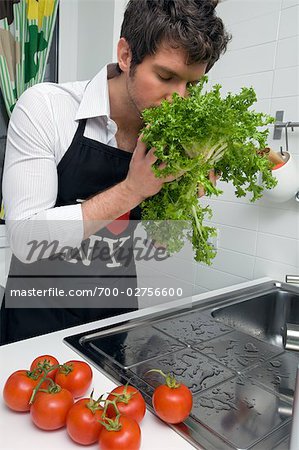 Man in Kitchen Washing Vegetables and Smelling Fresh Lettuce