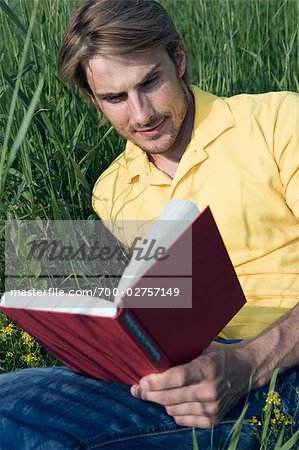 Man Sitting in Grass, Reading Book