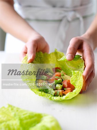 Woman Wrapping Chopped Avocado, Tomato and Cilantro in a Cabbage Leaf