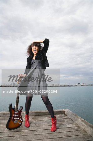 Woman Standing on Jetty holding Guitar