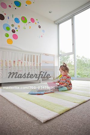 Baby Girl In Her Bedroom With A Pile Of Books Stock Photo