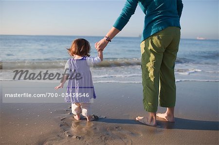 Back View of Mother holding Young Daughter's Hand, Standing on Beach, Long Beach, California, USA