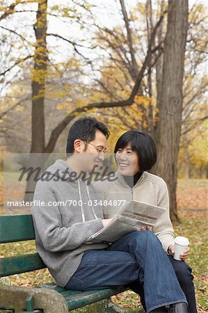 Couple Reading Newspaper on Park Bench