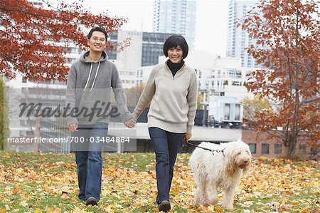 Couple Walking Dog in City Park in Autumn