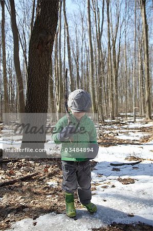 Boy Holding Stick in Forest in Winter