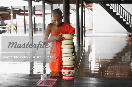 Young Monk Bringing Bowls to Table for Mealtime, Wat Luang,  Ubon Ratchathani, Thailand