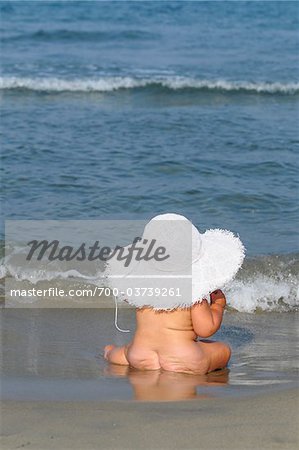 Young Beautiful Naked Woman Posing on a Stone Near the Sea Stock