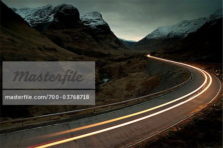 Trail of Car Lights at Dusk Through Mountainous valley, Glencoe, Scotland