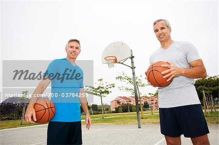 Two Men Holding Basketballs on Basketball Court