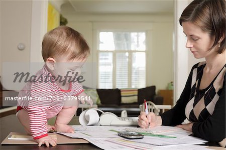 Woman Doing Paperwork with Baby on Table