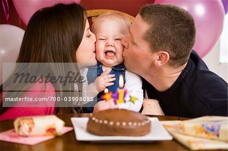 Parents Kissing Girl at First Birthday Party