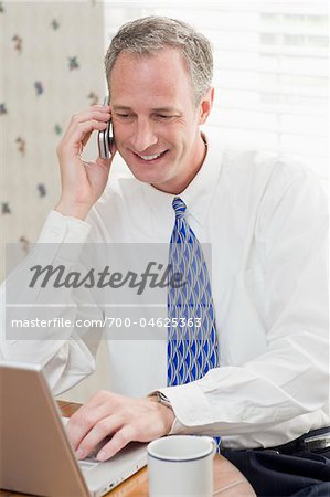 Businessman with Cell Phone and Laptop at Home