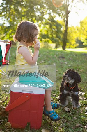 Girl Sitting on Cooler Eating Hamburger Girl Sitting on Cooler Eating Hamburger