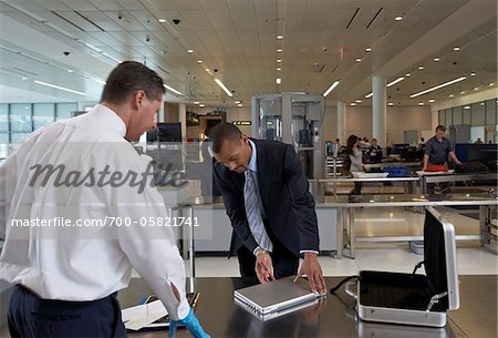 Businessman Opening Laptop for Security Guard in Airport