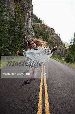 Young Woman Jumping in Middle of Road