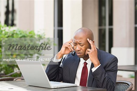 Stressed Businessman with Laptop and Cell Phone