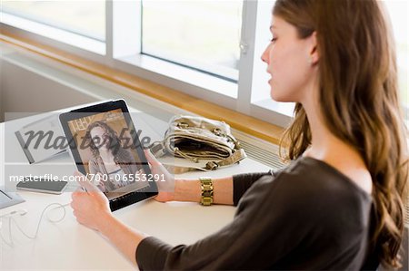 Woman in library using a tablet computer to have a video chat with her friend