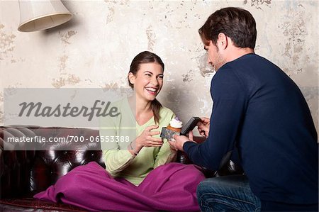 Young Man with Cupcake Proposing to Woman at Home