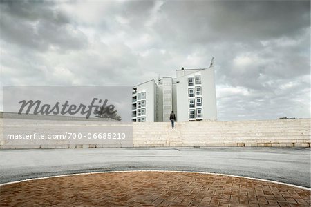 Man Walking Up Steps Towards Modern Building on Cloudy Overcast Day, Ostia Lido, Rome, Italy