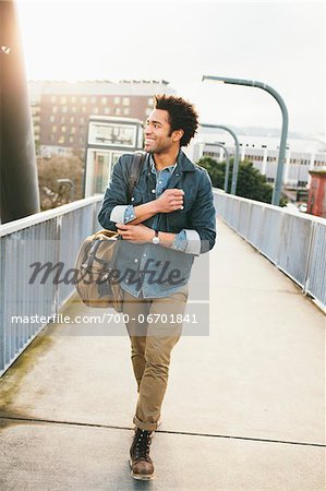 Smiling young man walking on foot bridge.