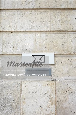 Close-Up of Mail Slot with Letter Symbol Sign on Cement Wall